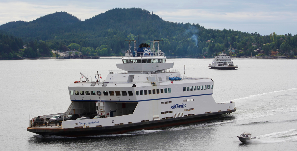 BC Ferries Queen of Cumberland design by Vard Marine sailing past an island with another ferry in the distance and small boat alongside